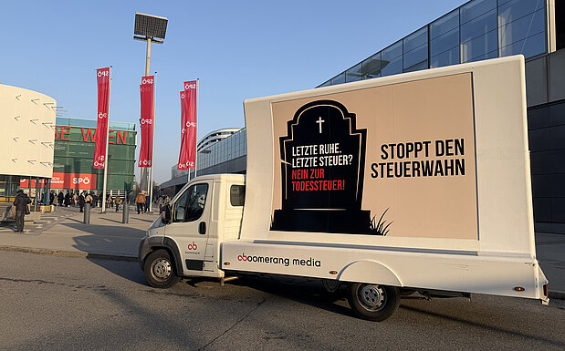 Ein Werbe-LKW mit einem Plakat gegen eine „Todessteuer“ steht vor der Messe Wien, während Menschen im Hintergrund zum SPÖ-Parteitag gehen