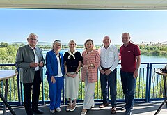 Auf diesem Gruppenfoto sind zu sehen, von links beginnend: Bürgermeister Alfred Riedl, eine Dolmetscherin, Hanna Zamazeeva, Leiterin der ukrainischen Energieagentur, IV-NÖ-Geschäftsführerin Michaela Roither, Helwig Überacker, bei der EVN zuständig für Windkraft-, PV- und Wasserkraftprojekte, und EVN-Kommunikationschef Stefan Zach. Die Aufnahme wurde  vor dem Hintergrund der Floating-Photovoltaikanlage in Grafenwörth gemacht.