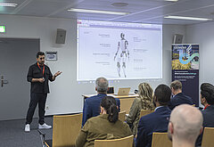 Ein Vortragender präsentiert vor Teilnehmerinnen und Teilnehmern der IV-NÖ-Fokusgruppe „Künstliche Intelligenz & Digitalisierung“ konkrete Anwendungen humanoider Robotik; im Hintergrund eine Präsentationsfolie mit technischen Spezifikationen, aufgenommen in der Siemens City Wien.