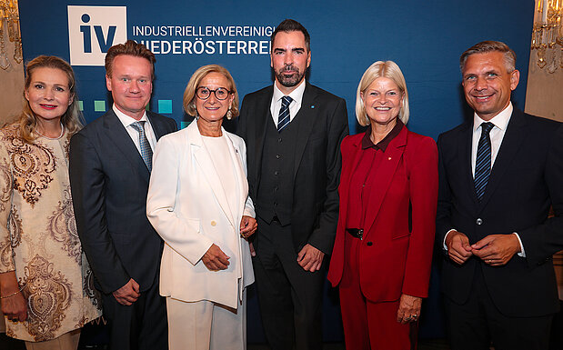 Gruppenfoto beim „Tag der NÖ Industrie“ vor einem Roll-up der Industriellenvereinigung Niederösterreich: (v.l.n.r.) IV-NÖ-Geschäftsführerin Michaela Roither, IV-Präsident Georg Knill, Niederösterreichs Landeshauptfrau Johanna Mikl-Leitner, IV-NÖ-Präsident Kari Ochsner, Verteidigungsministerin Klaudia Tanner und Wirtschaftsminister Wolfgang Hattmannsdorfer stehen nebeneinander und blicken in die Kamera.