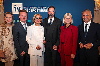 Gruppenfoto beim „Tag der NÖ Industrie“ vor einem Roll-up der Industriellenvereinigung Niederösterreich: (v.l.n.r.) IV-NÖ-Geschäftsführerin Michaela Roither, IV-Präsident Georg Knill, Niederösterreichs Landeshauptfrau Johanna Mikl-Leitner, IV-NÖ-Präsident Kari Ochsner, Verteidigungsministerin Klaudia Tanner und Wirtschaftsminister Wolfgang Hattmannsdorfer stehen nebeneinander und blicken in die Kamera.
