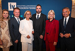 Gruppenfoto beim „Tag der NÖ Industrie“ vor einem Roll-up der Industriellenvereinigung Niederösterreich: (v.l.n.r.) IV-NÖ-Geschäftsführerin Michaela Roither, IV-Präsident Georg Knill, Niederösterreichs Landeshauptfrau Johanna Mikl-Leitner, IV-NÖ-Präsident Kari Ochsner, Verteidigungsministerin Klaudia Tanner und Wirtschaftsminister Wolfgang Hattmannsdorfer stehen nebeneinander und blicken in die Kamera.