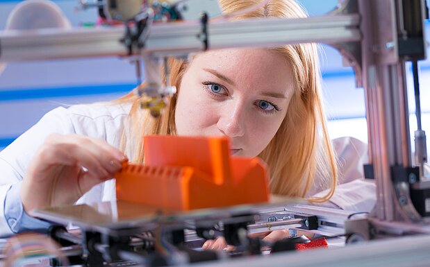 Junge Frau arbeitet mit 3D-Drucker